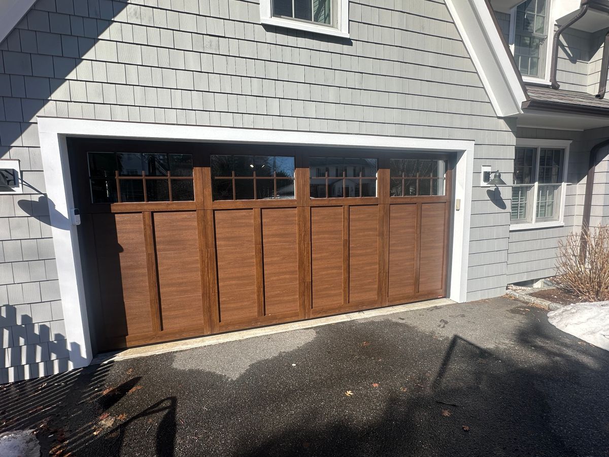 Custom wood garage door with transom windows on gray colonial home in Chelmsford, MA