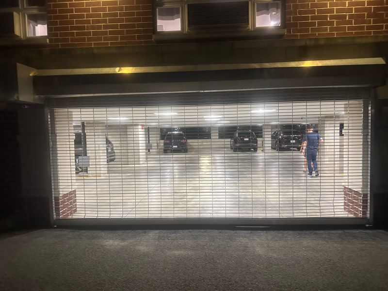 Parking garage security grille door at night with vehicles inside — Massachusetts