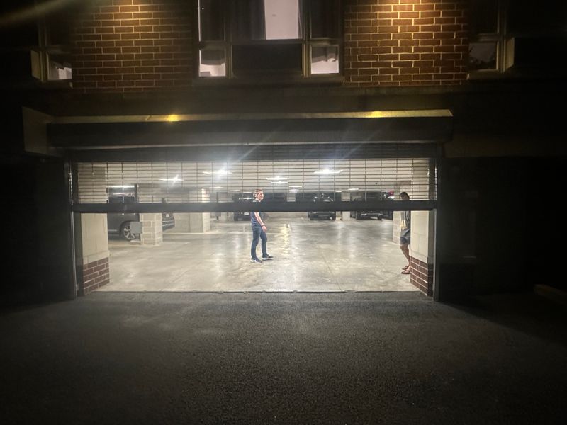 Parking garage security grille partially open at night showing interior — MA